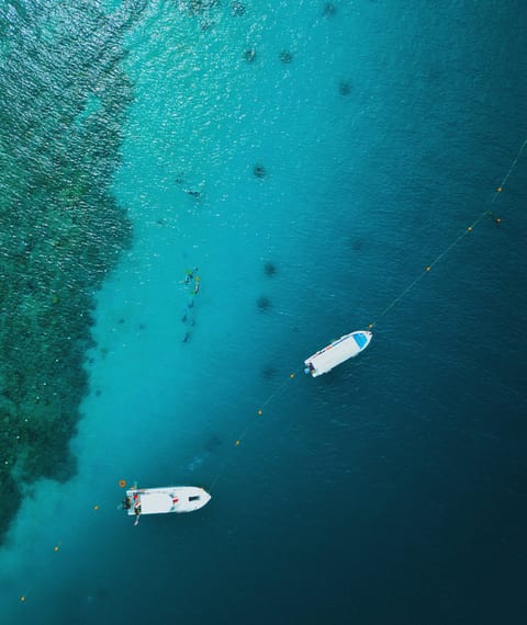 Corals and boats on blue water in Borneo