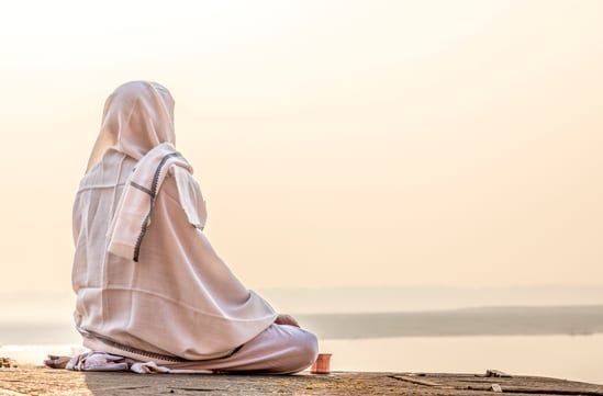 woman meditating by the ganges in varanasi in india