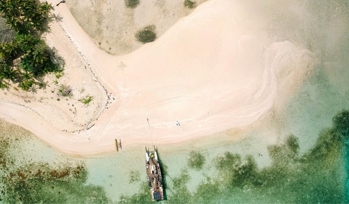 An overhead shot of one of the beaches on Fiji with traditional boat on Australasia