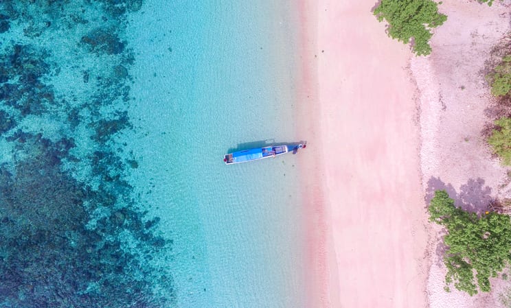 Blue boat docked on the pink sand on the island of Komodo, Indonesia