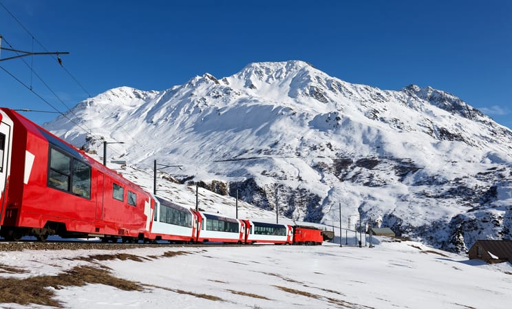 Glacier Express train against snow capped mountains