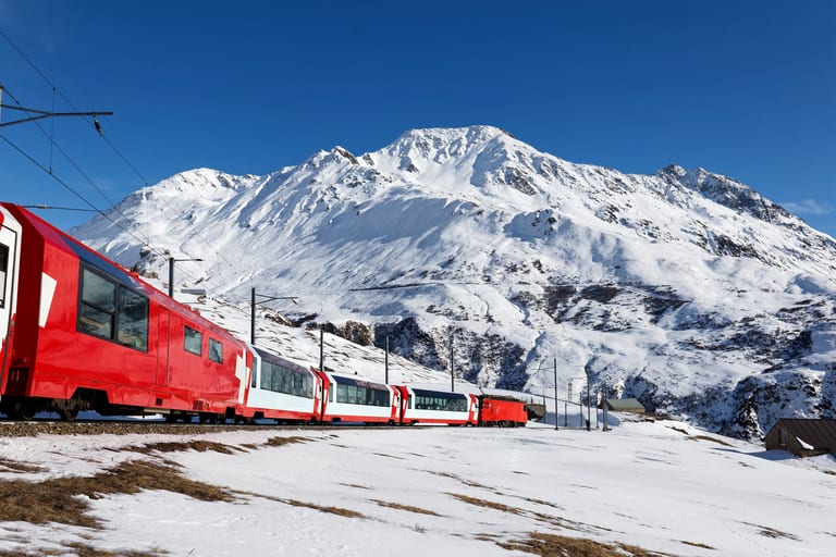 Glacier Express train against snow capped mountains